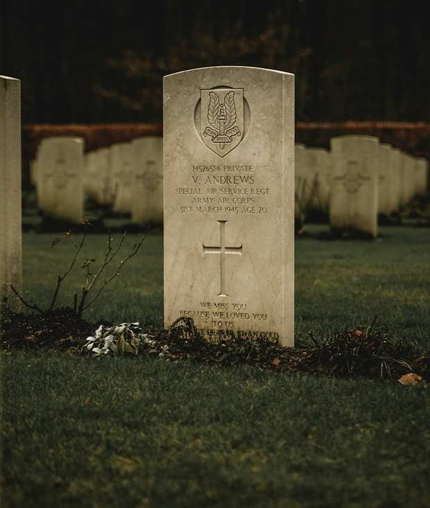 A pale headstone standing clean in mown grass, its inscription sharp